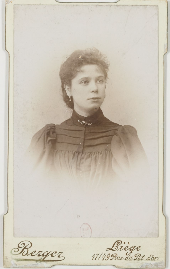 Portrait of a woman in a high neck dress with curly hair. She is looking away from the camera.